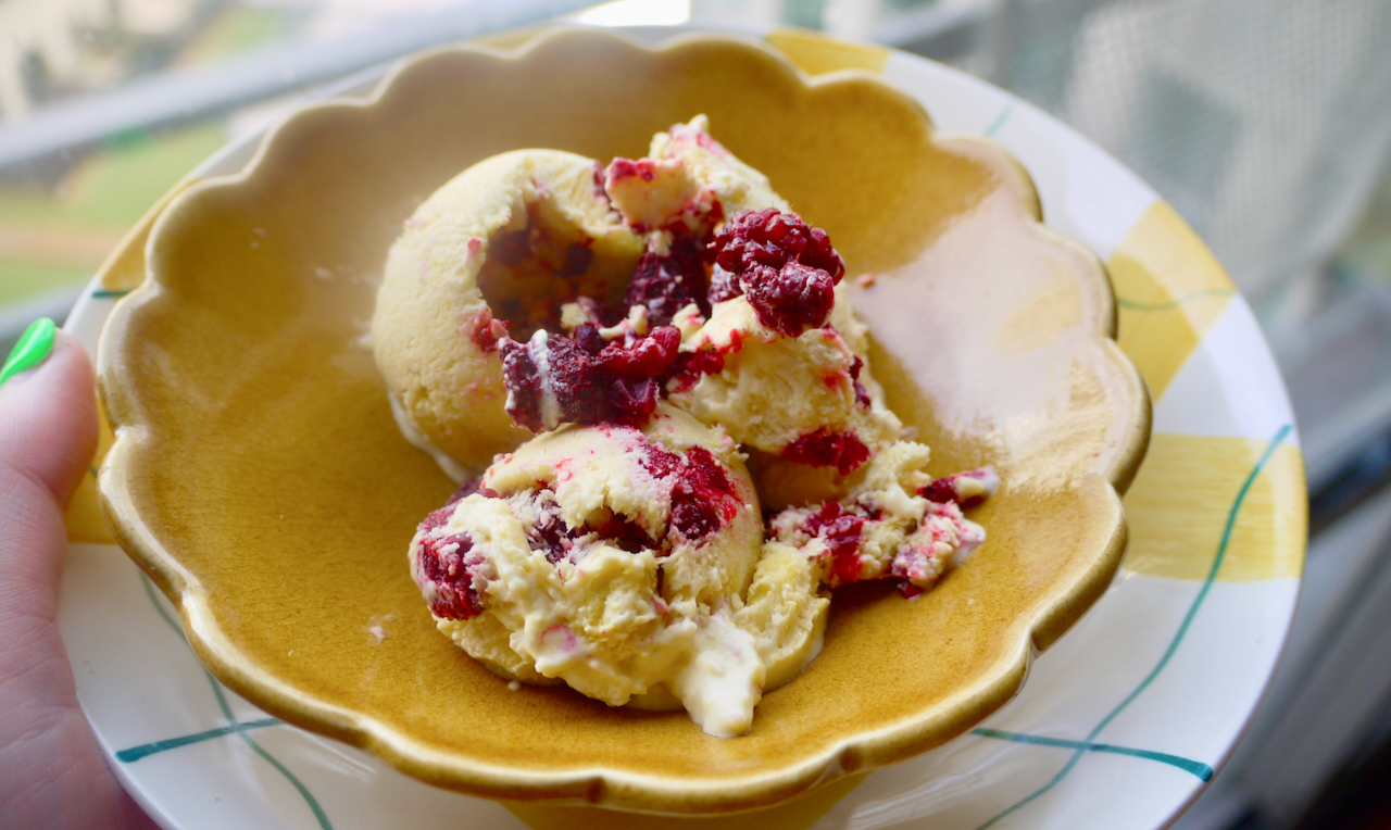 a hand with bright green nails holding a bowl of ice cream