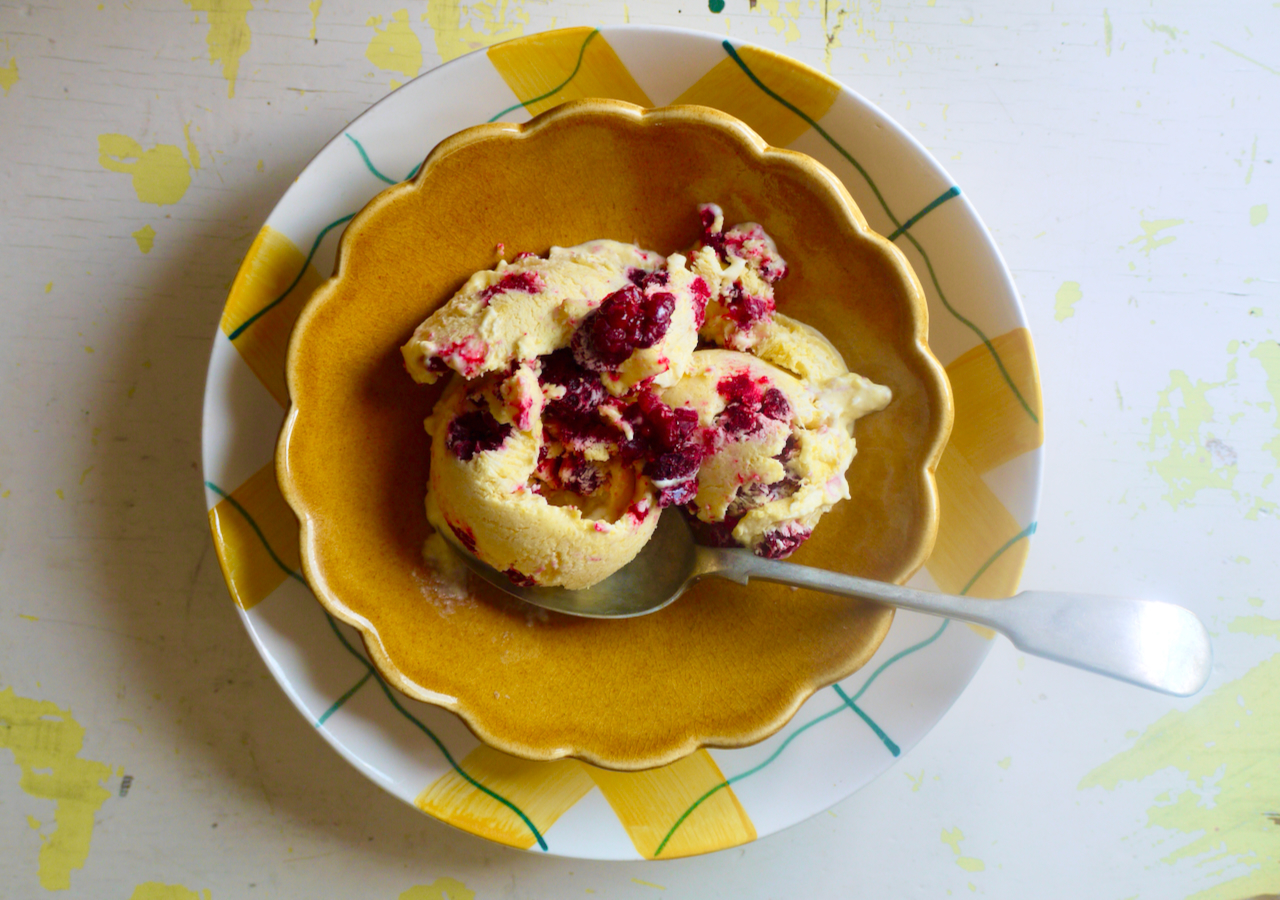 a landscape topdown shot of ice cream in a scallopped bowl with a spoon, against a white background