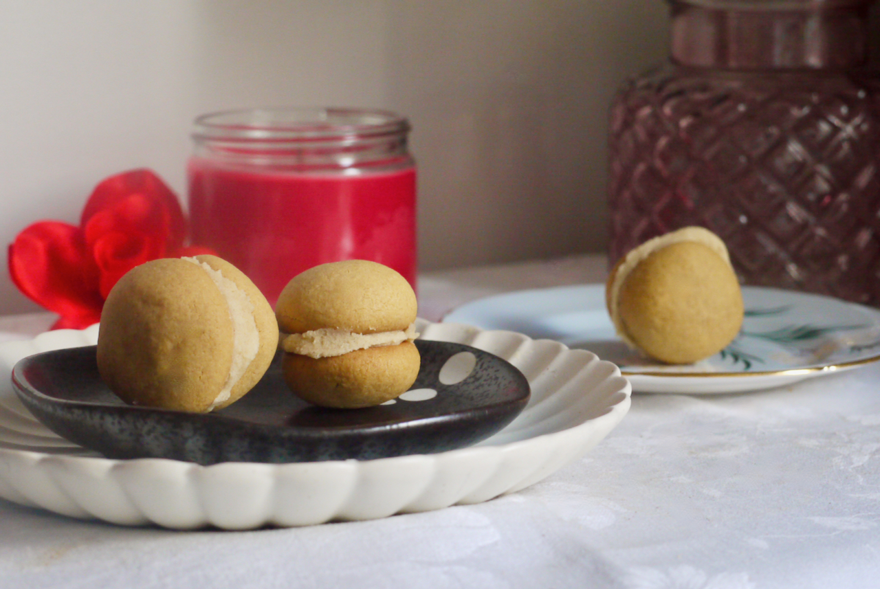 Cookies on a plate with a red candle in the background on a white tablecloth