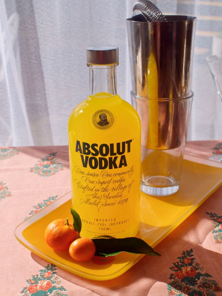 A bottle of liqueur on an orange plate, with cockail shakers in the background and mandarins in the foreground. This image links through to a web page with the recipe.