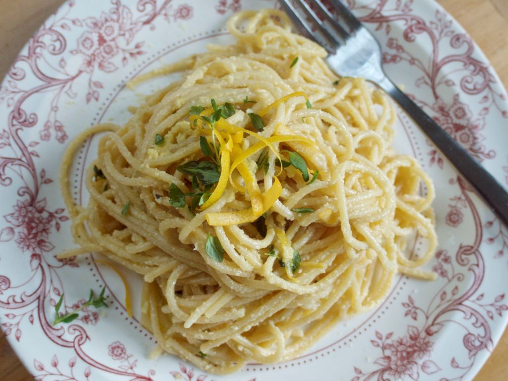 A pink and white plate of spaghetti with a fork resting on it, and shreds of lemon zest on top. This image links through to a web page with the recipe.