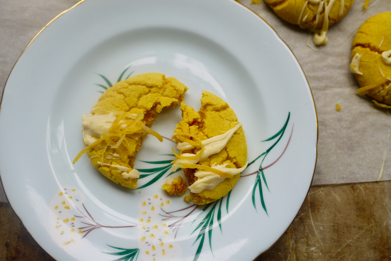a broken lemon turmeric cookie on a blue plate with white flowers on it
