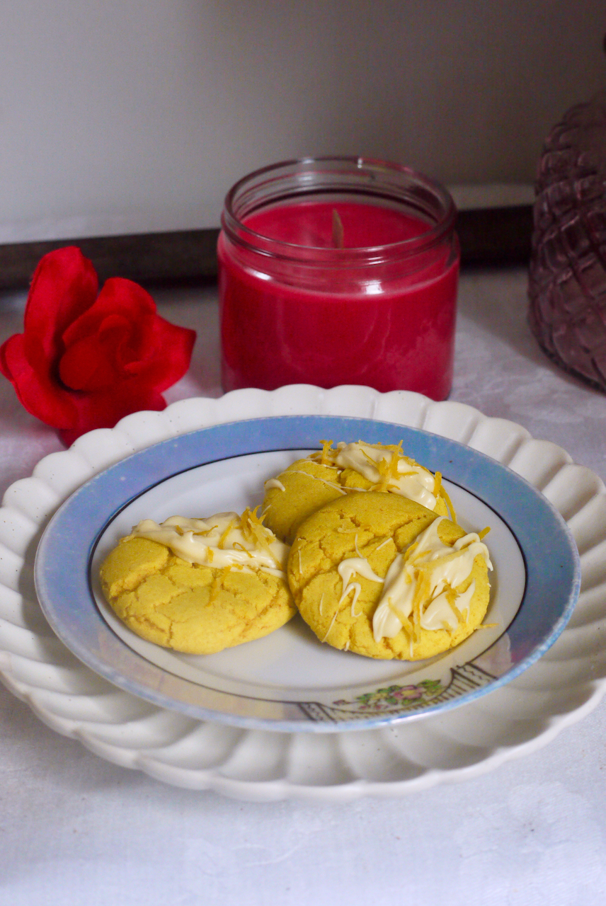 three lemon turmeric cookies on a white plate with a blue border