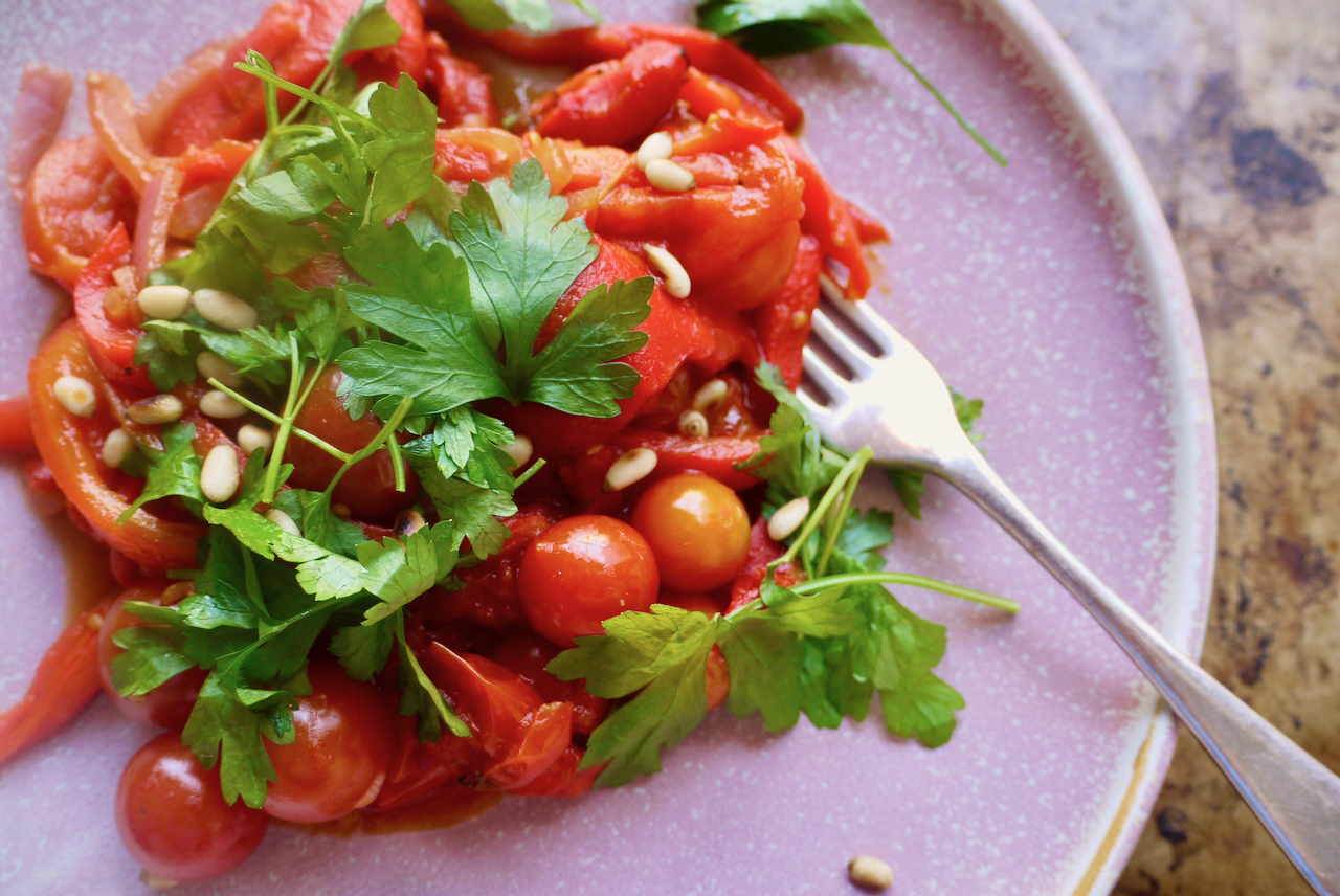 a pink plate of piperade close up with a fork on it