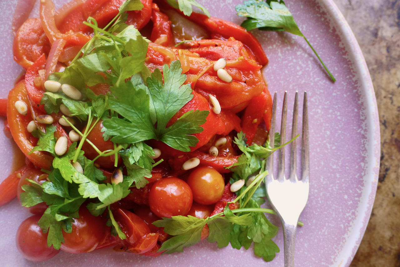 a pink plate of piperade with parsley on top