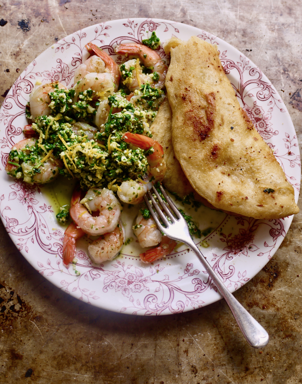 Prawns, rocket, and flatbread on a tray with a fork on a pink and white plate