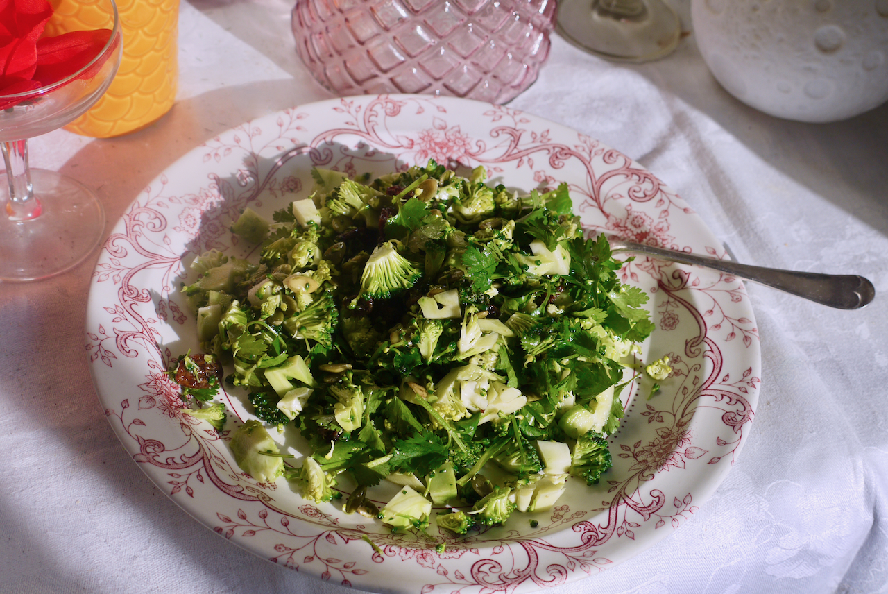 a white and pink plate of broccoli salad on a white tablecloth