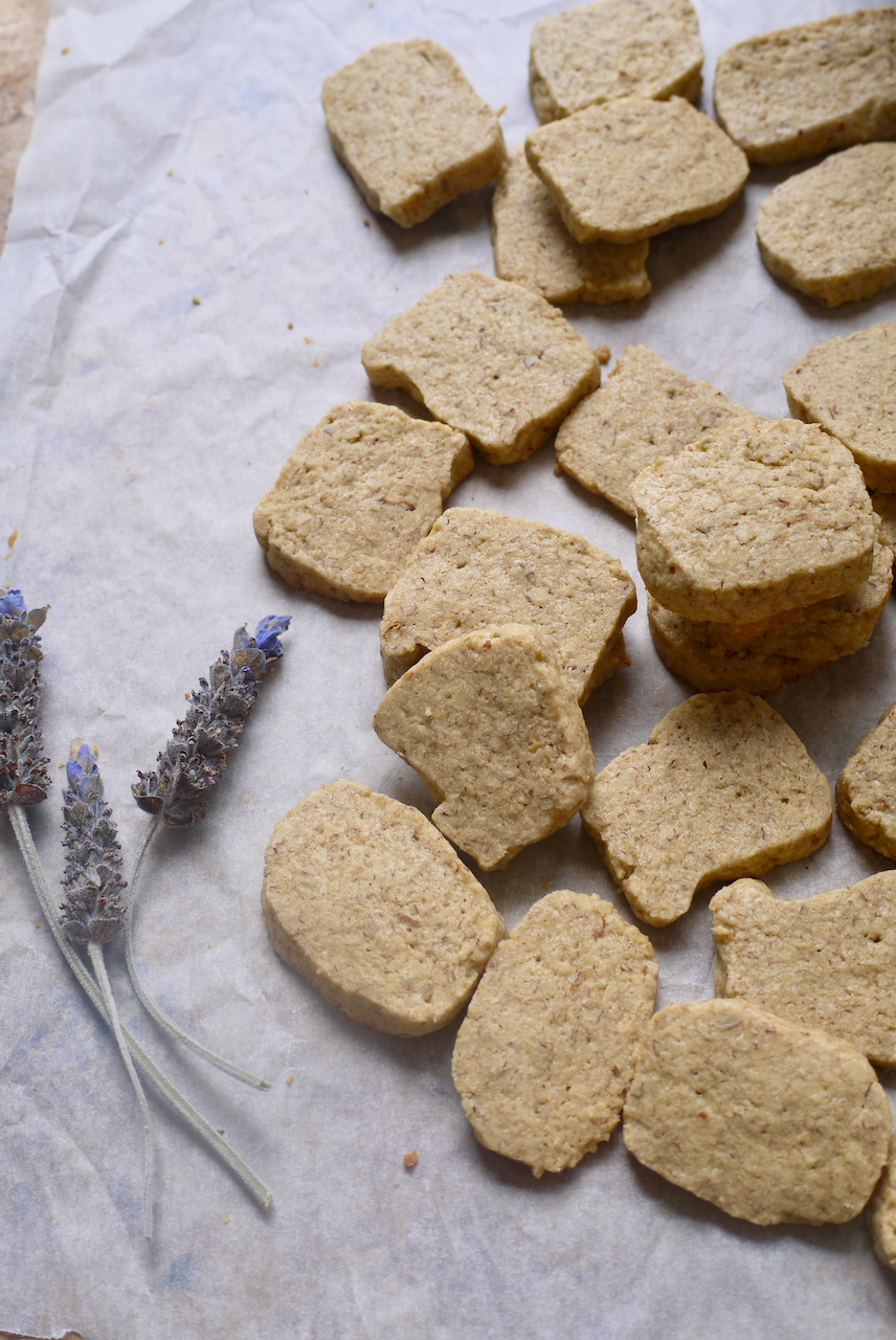 three sprigs of lavender beside a baking paper lined tray of biscuits