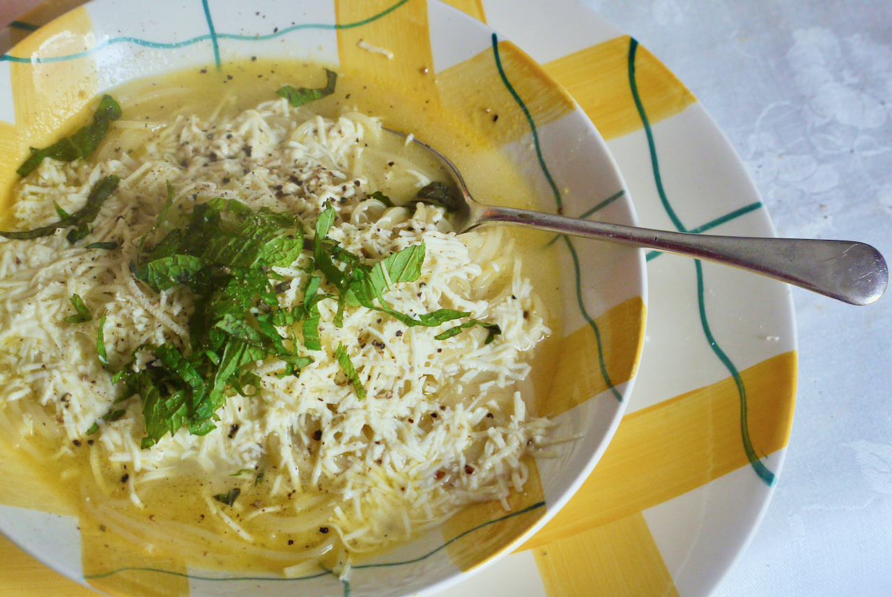 A spoon resting in a yellow bowl of soup