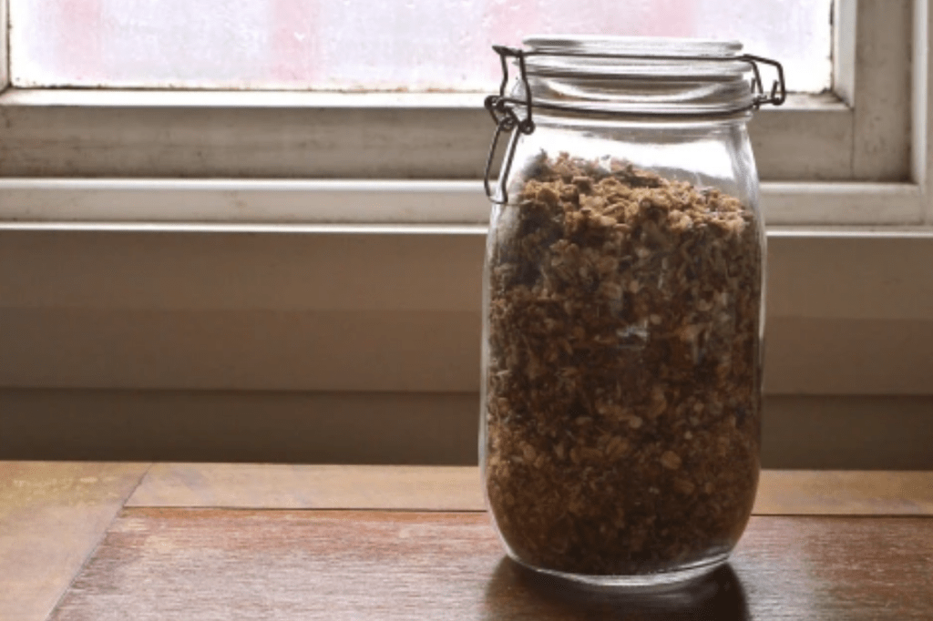 A jar of granola on a table. This image links through to a web page with the recipe. 