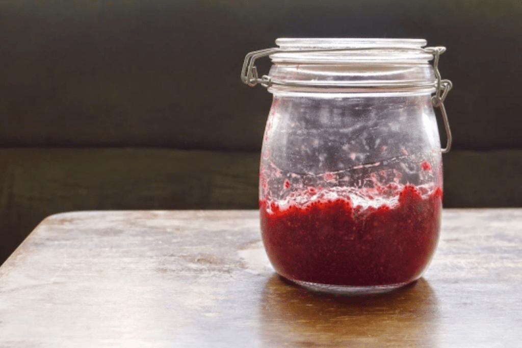 A jar of berry chia seed jam on a table. This image links through to a web page with the recipe.