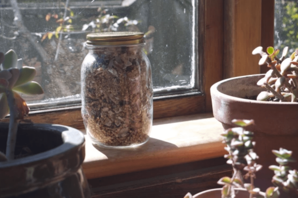 Jar of granola on a windowsill. This image links through to a web page with the recipe. 