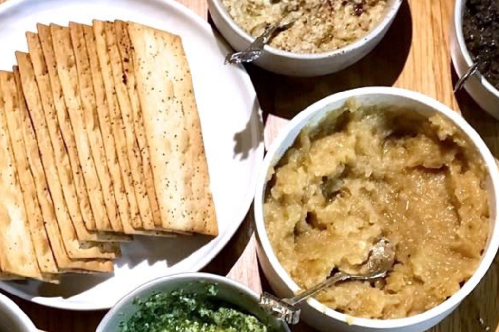 A bowl of caramelised onion butter next to a plate of crackers. This image links through to a web page with the recipe.