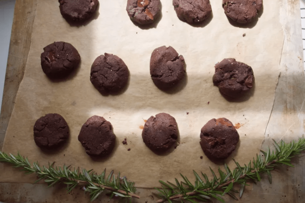 Chocolate cookies on a tray with sprigs of rosemary. This image links through to a web page with the recipe.