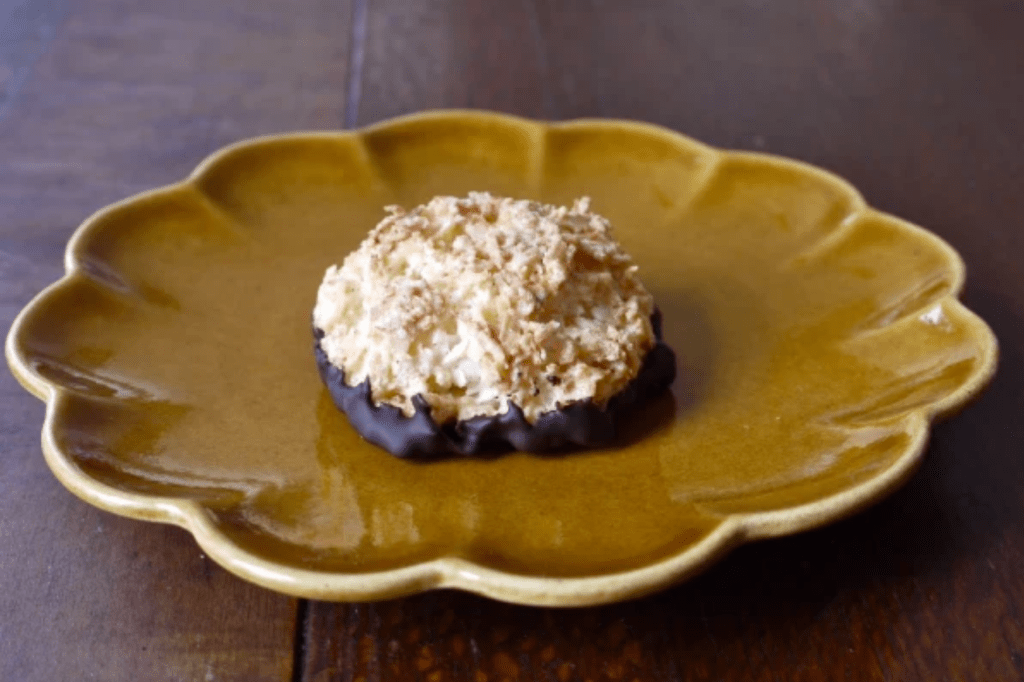 A chocolate-dipped macaroon on an ochre plate. This image links through to a web page with the recipe.