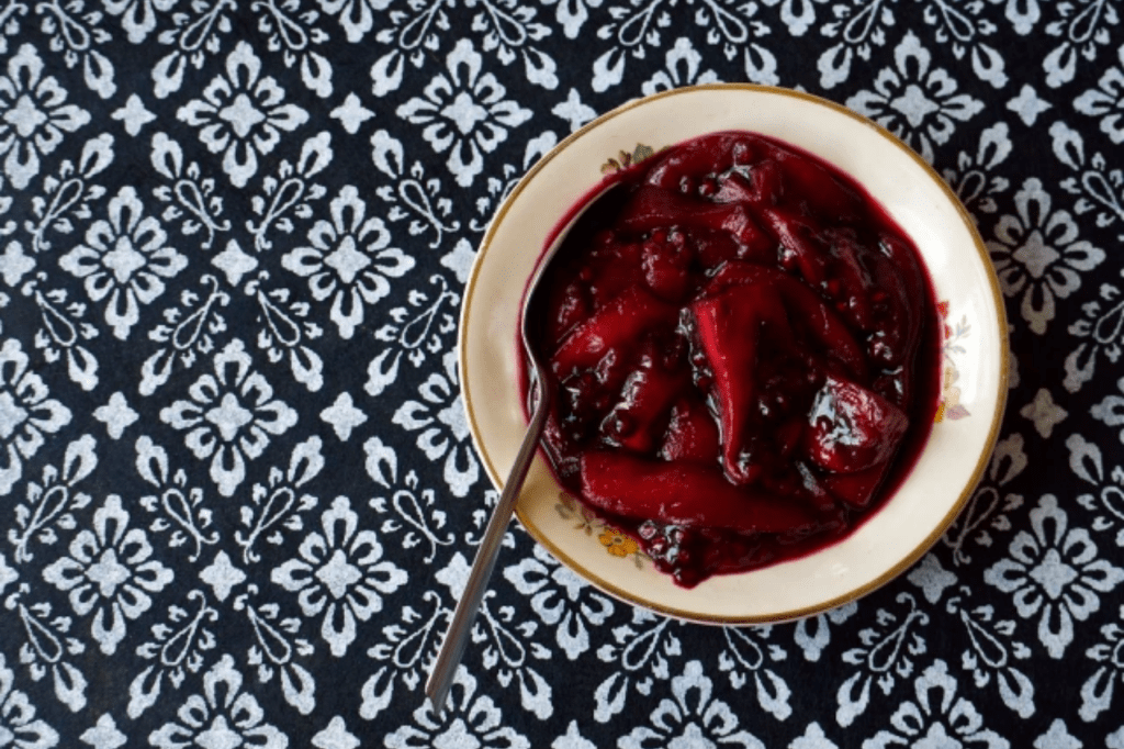 A small bowl of marinated tamarillos on a black and white patterned background. This image links through to a web page with the recipe.