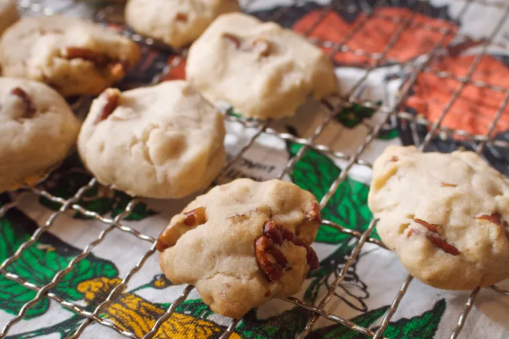 Pecan cookies on a cooling rack over a colourful teatowel. This image links through to a web page with the recipe.