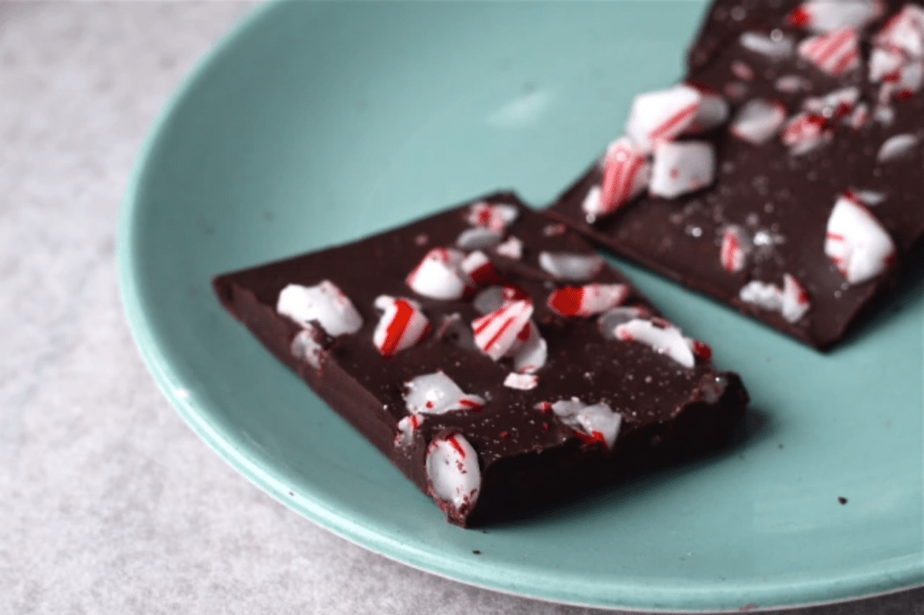 Two pieces of peppermint chocolate bark on a green plate. This image links through to a web page with this recipe.