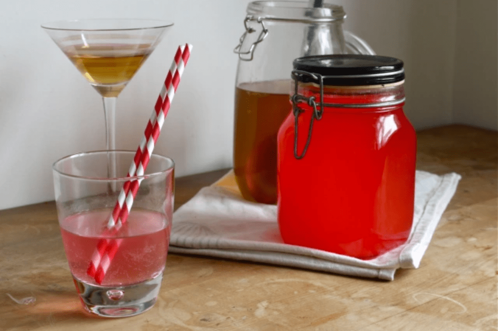 A jar of peppermint schnapps with a glass of schnapps and two red and white striped straws. This image links through to a web page with this recipe.