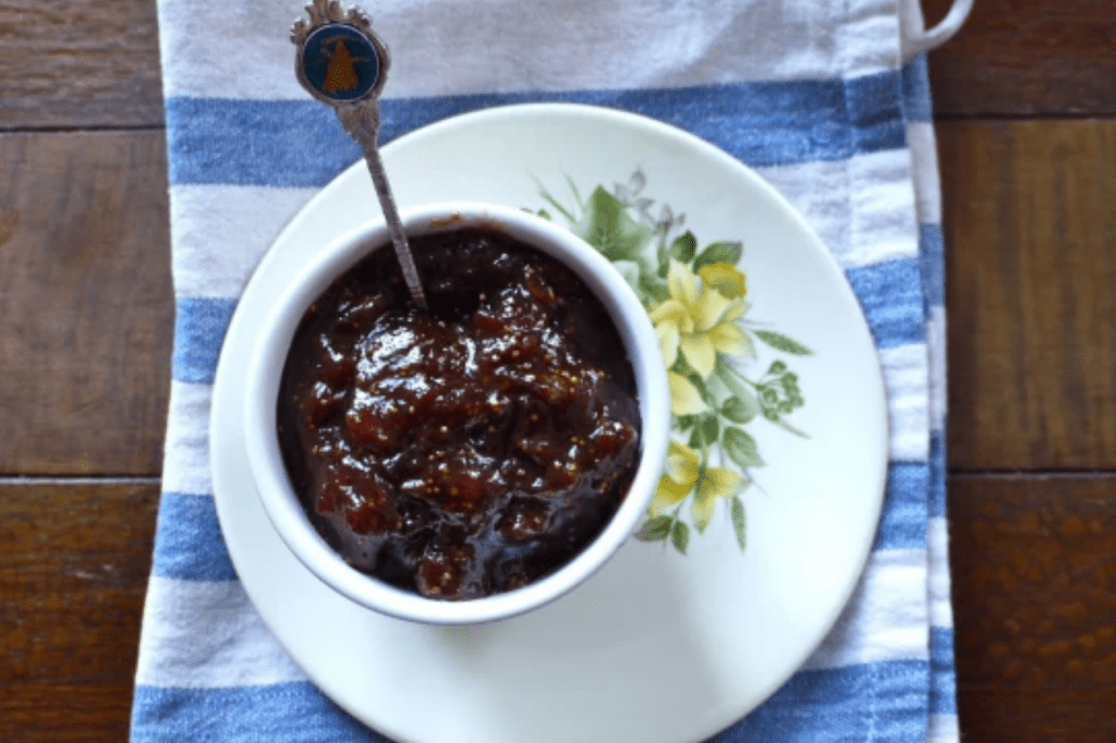 A bowl of rhubarb and fig jam with a teaspoon on a blue and white cloth. This image links through to a web page with the recipe.