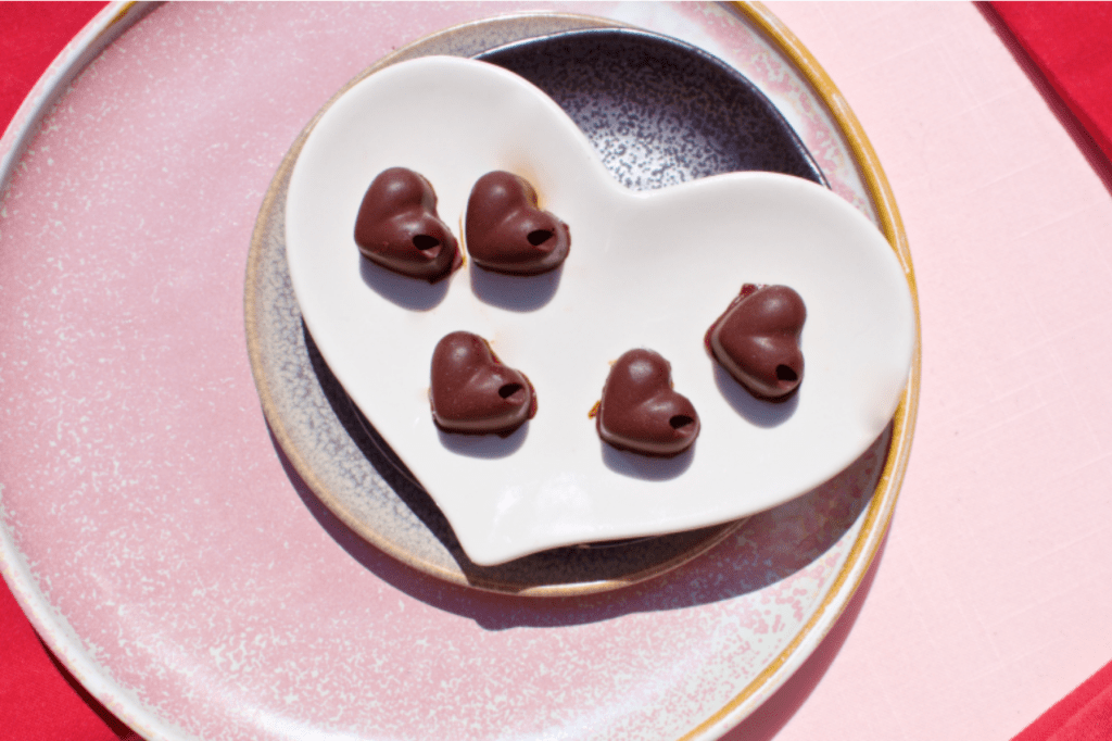 A heart shaped plate of heart chocolates on a pink background. This image links through to a web page with this recipe.
