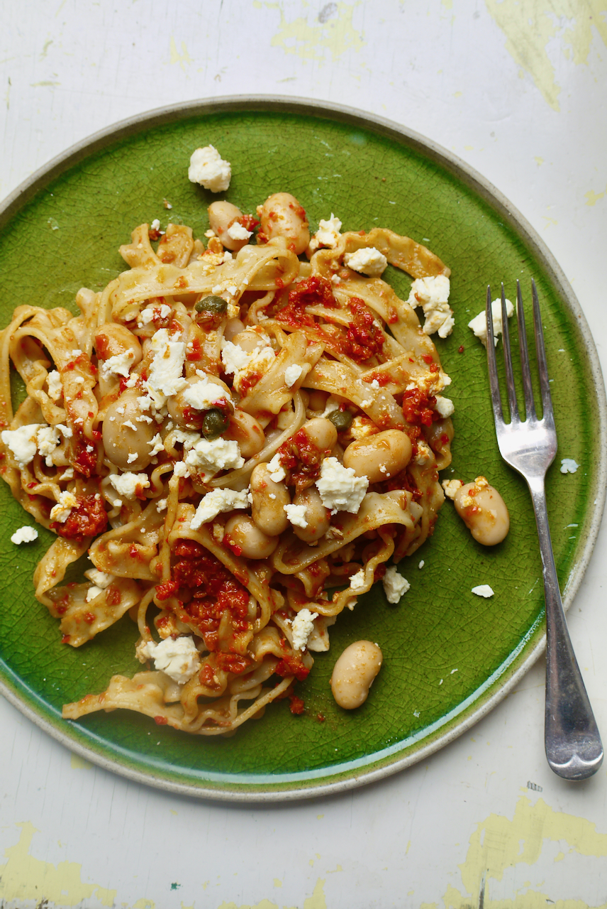A green plate with pasta and a fork on a white background