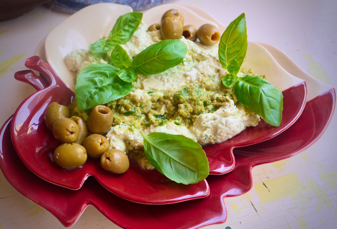 A leaf shaped plate of dip on a white background