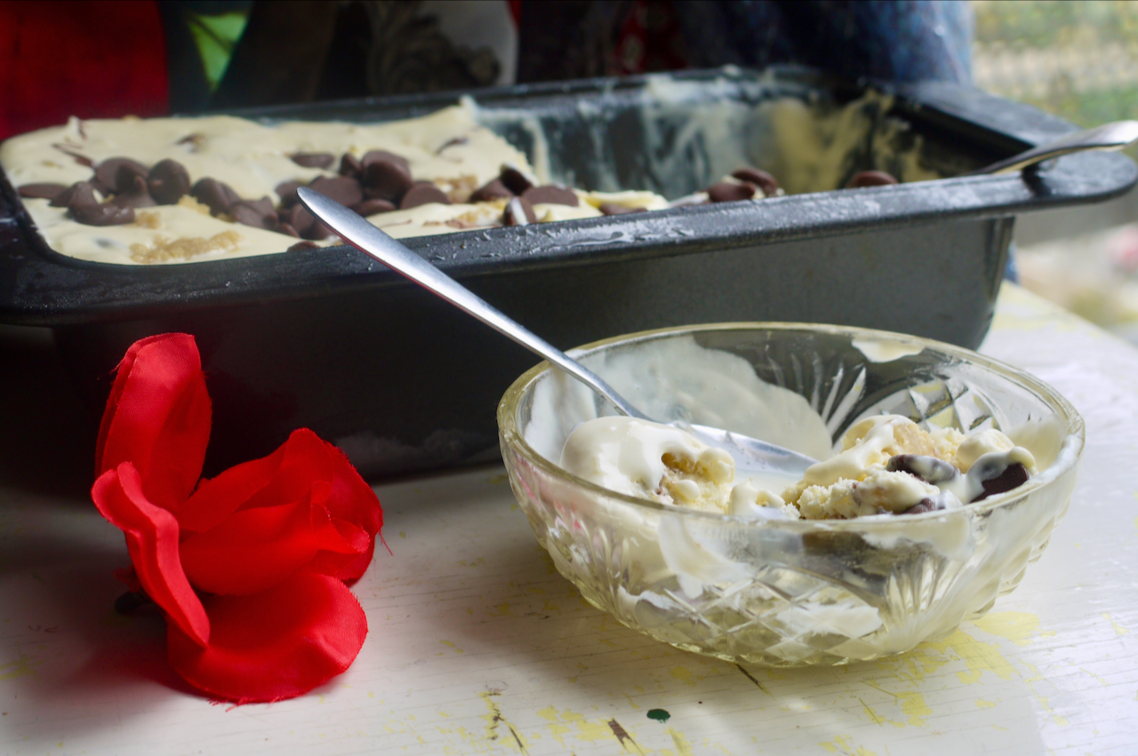 a small glass bowl of ice cream with a red fabric rose