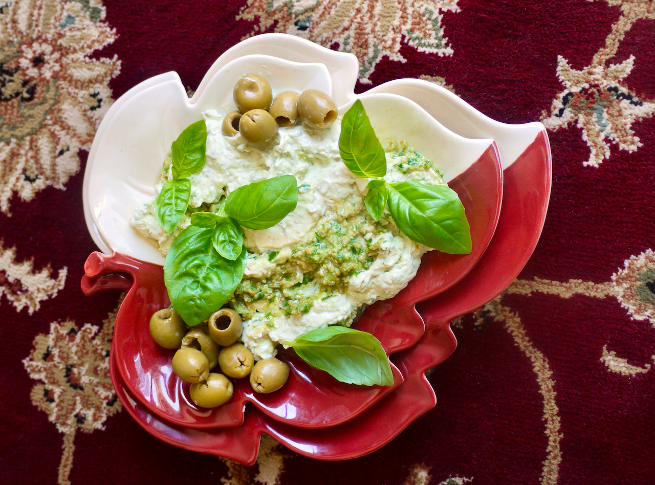 Two leaf-shaped plates with dip and basil leaves on red carpet background