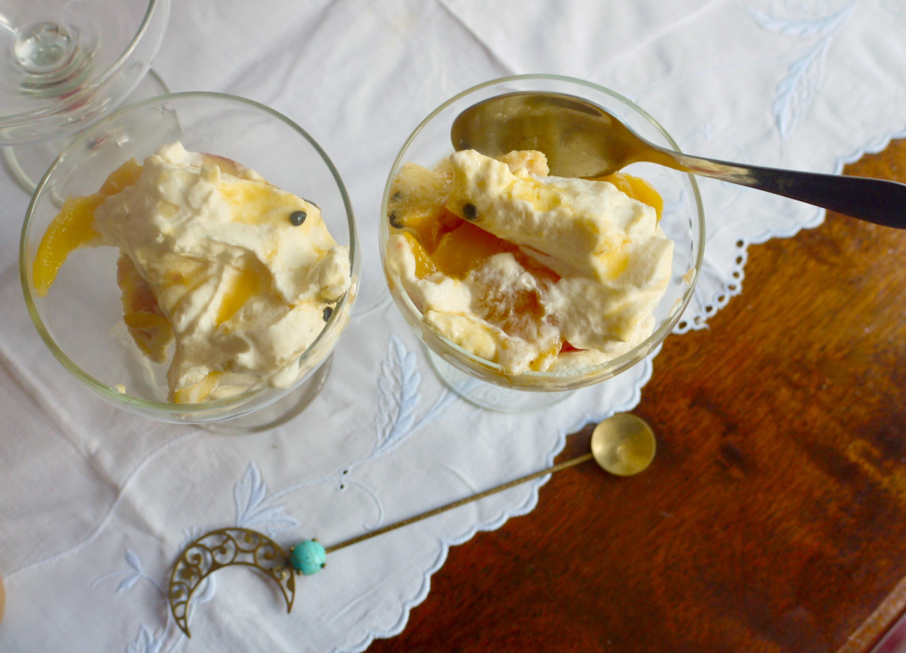 two coupe glasses of trifle, one with a teaspoon in it