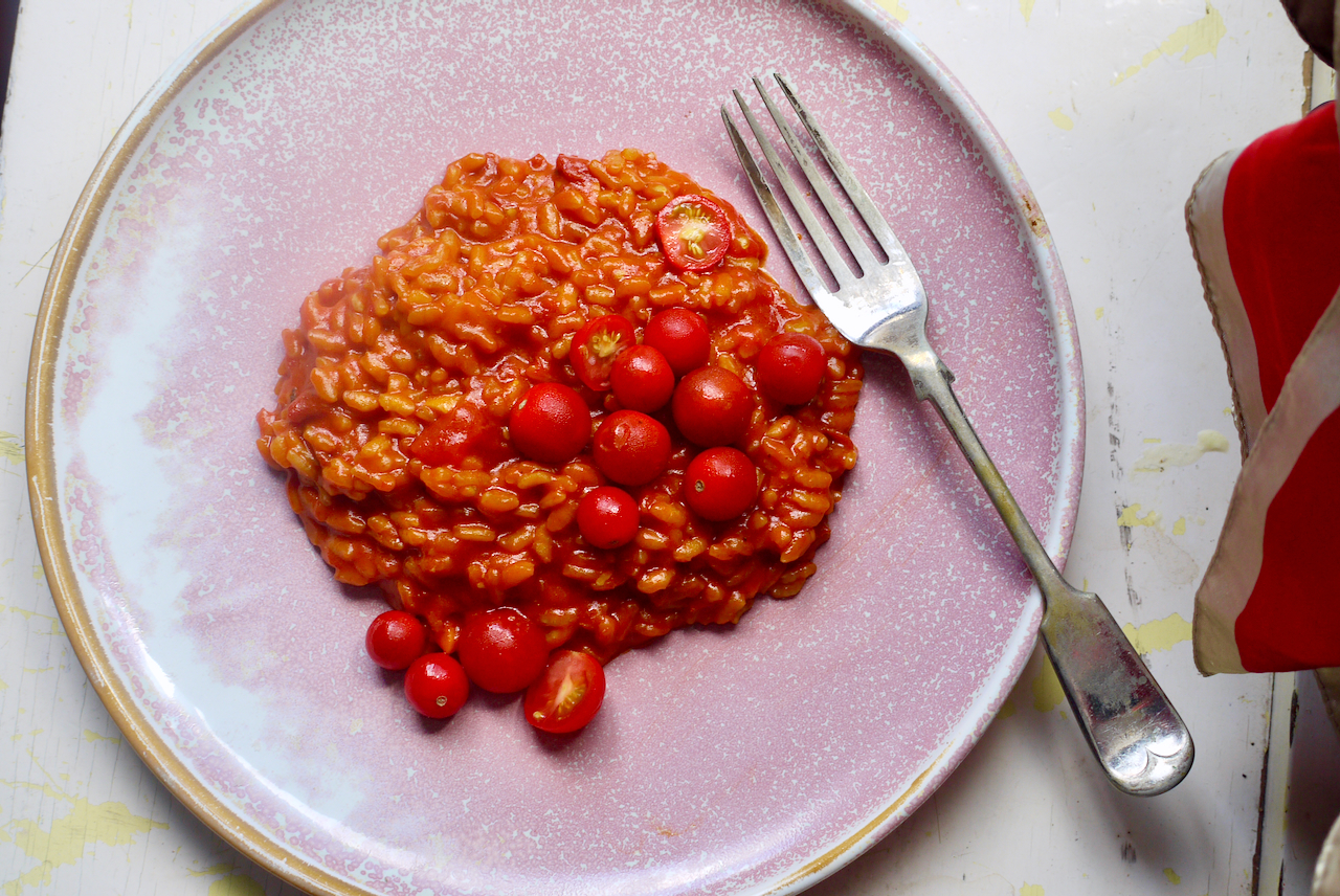 Tomato risotto and a fork on a pink plate