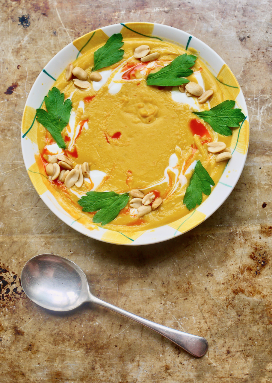 butternut soup with garnishes and a soup spoon on a metal baking sheet with a soup spoon