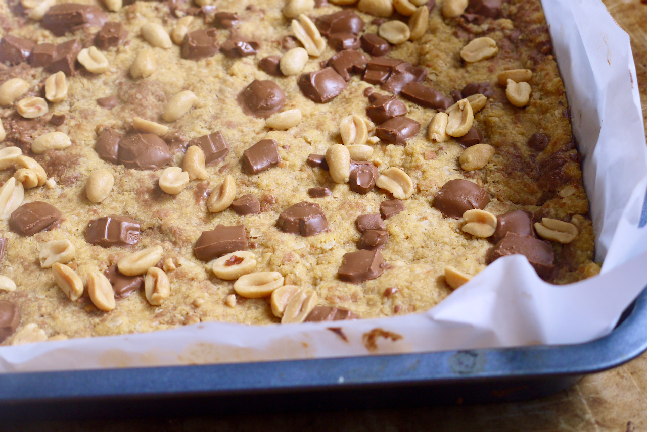 unsliced peanut butter chocolate chunk squares with chopped chocolate and peanuts on top