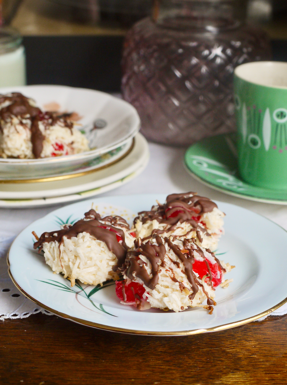A blue plate with three macaroons on it, with a green coffee cup behind it