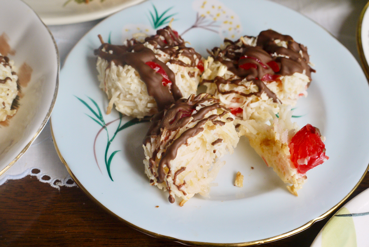 A cherry macaroon broken in half on a blue plate