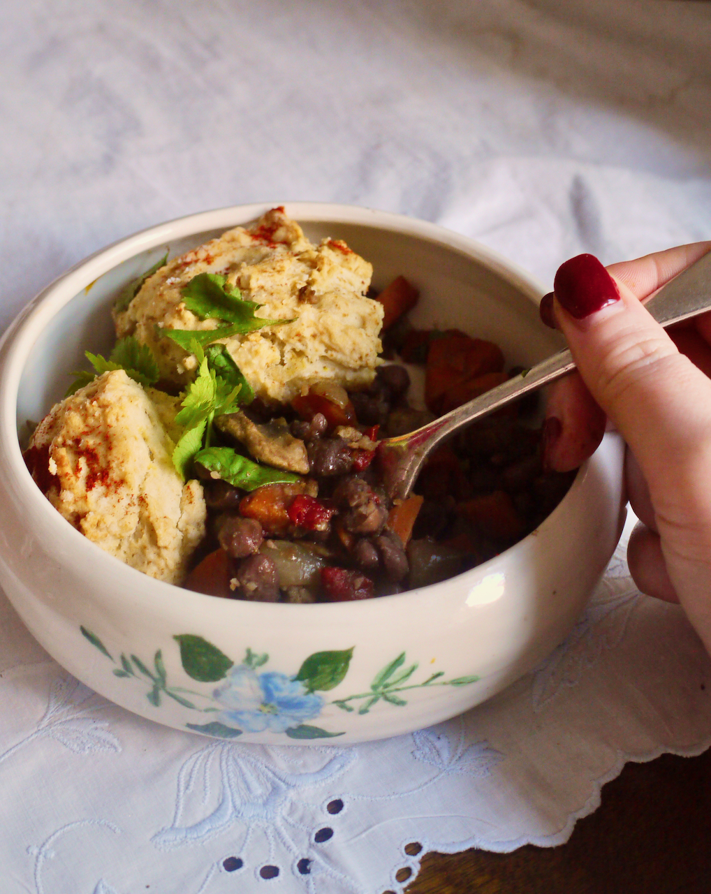 A hand with red nails getting a spoonful of black bean cobbler