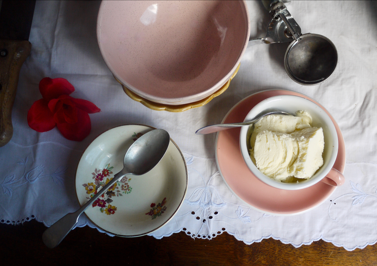 a pink teacup of ice cream, a pink bowl, an ice cream scoop and a red fabric rose