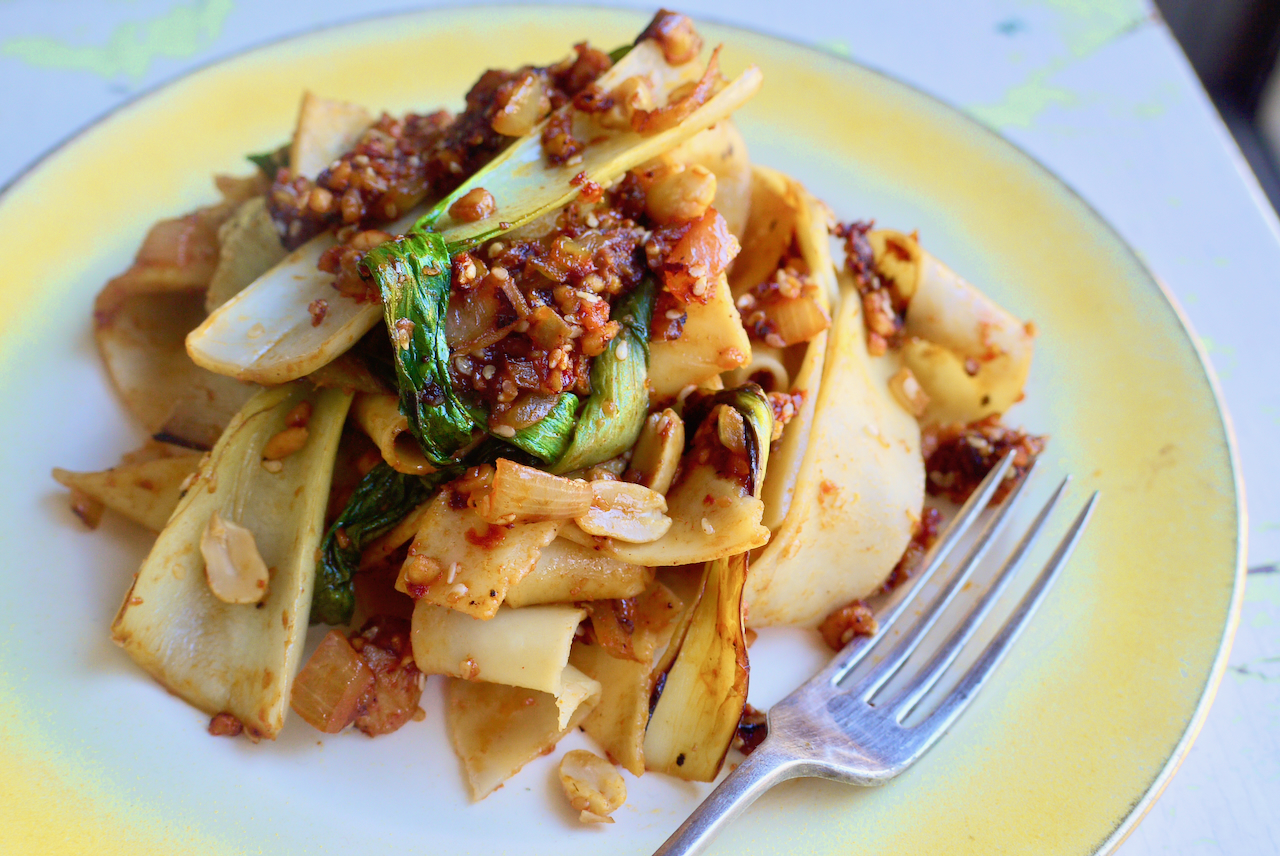 a fork resting on a yellow and white plate of noodles