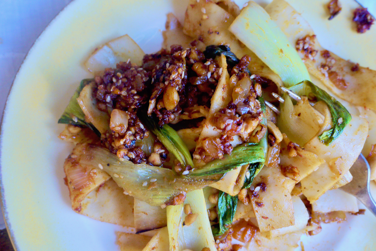 a mound of noodles with vegetables on a yellow and white plate