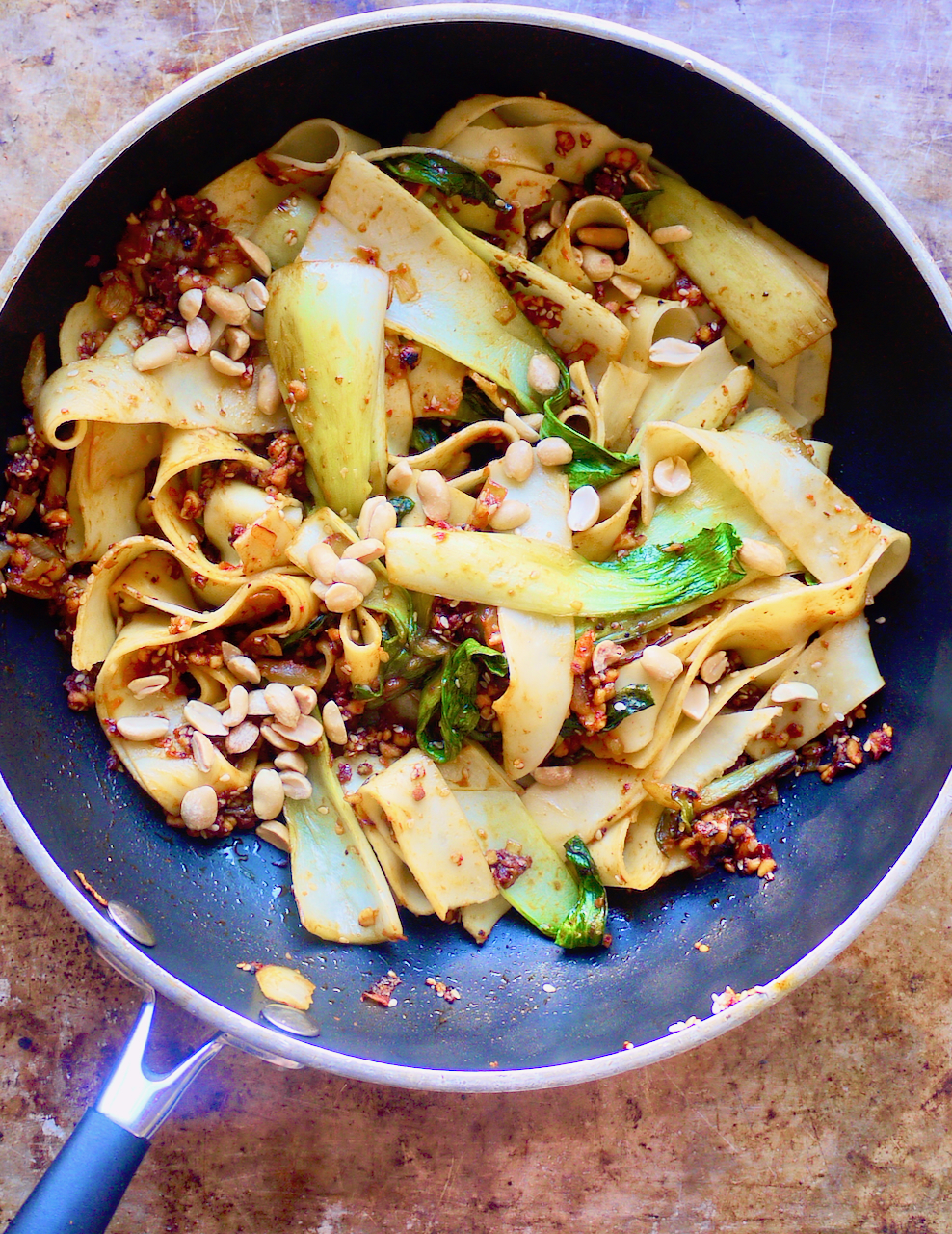 A portrait shot of a pan of vegetables and noodles