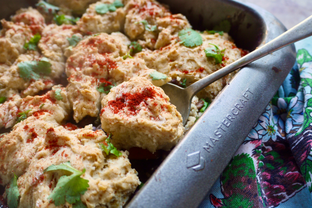 A baking dish of black bean cobbler with a spoon scooping out a portion. This image links to a web page with this recipe.