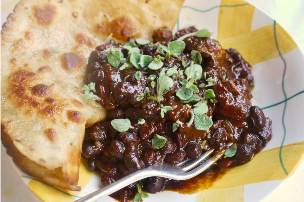Guinness beef chilli and flatbread in a yellow and white bowl. This image links to a web page with this recipe.