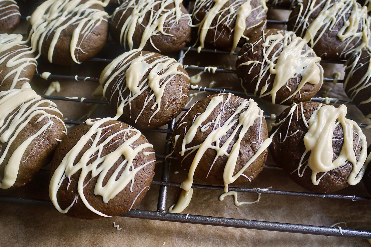 Molasses cookies drizzled with white chocolate on a rack