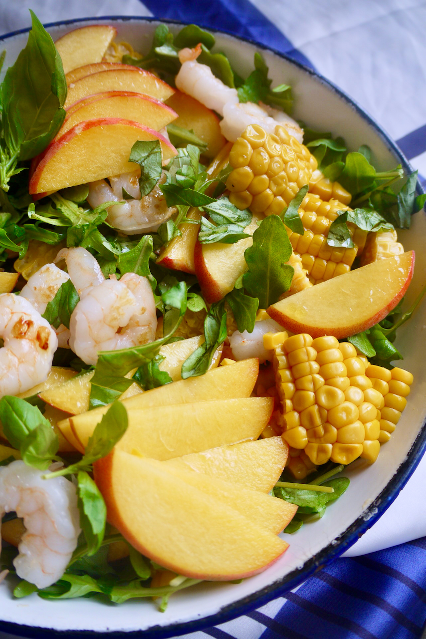Sliced peaches fannning out on a corn, prawn and peach salad