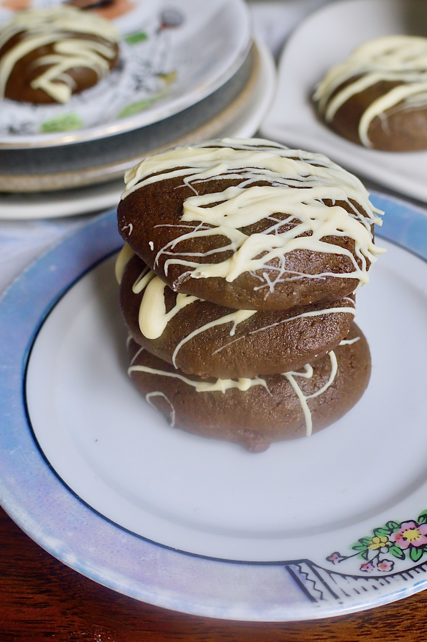 Three molasses cookies stacked on top of each other on a white plate with a blue rim