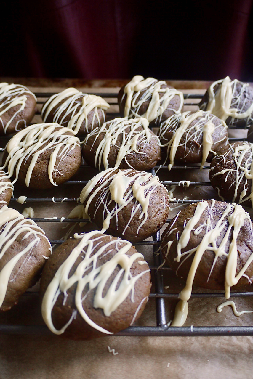 White chocolate-drizzled molasses cookies on a cooling rack
