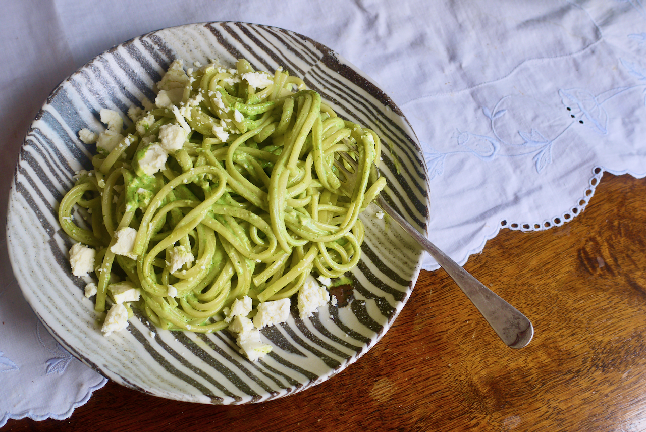 A black and white plate of tallarines verdes on a white tablecloth