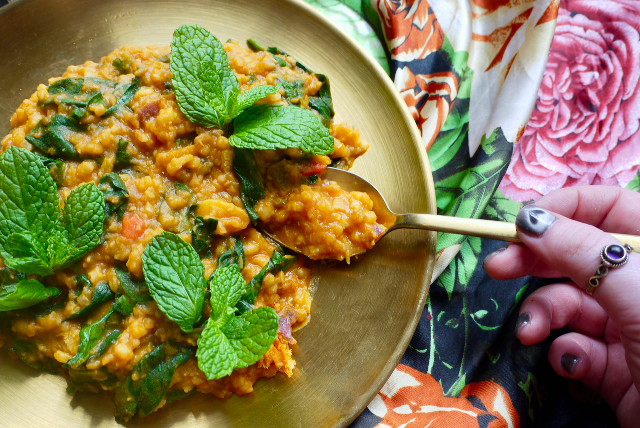 A hand with grey painted nails holding a spoonful of sha'aktoura