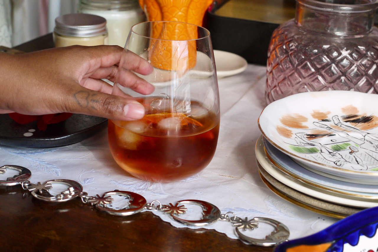 a hand with a heart tattoo on the thumb reaching for a cocktail