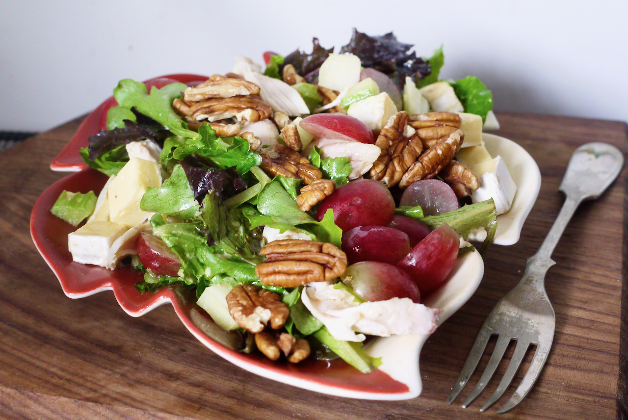 A salad on a dark wooden board with a fork next to it